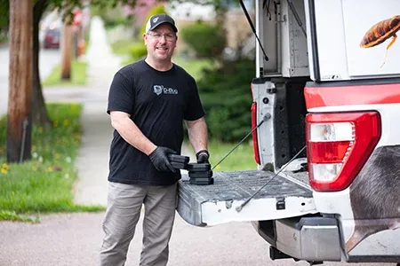 D-Bug Pest technician standing next to truck smilling